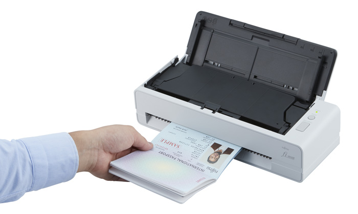 Passport Scanning Scanner with man's hand holding a passport that was just fed through the scanner