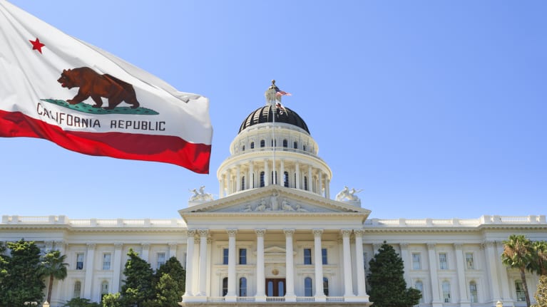 Image representing AB 1466 of the California statehouse with the California Republic flag waving in the blue sky